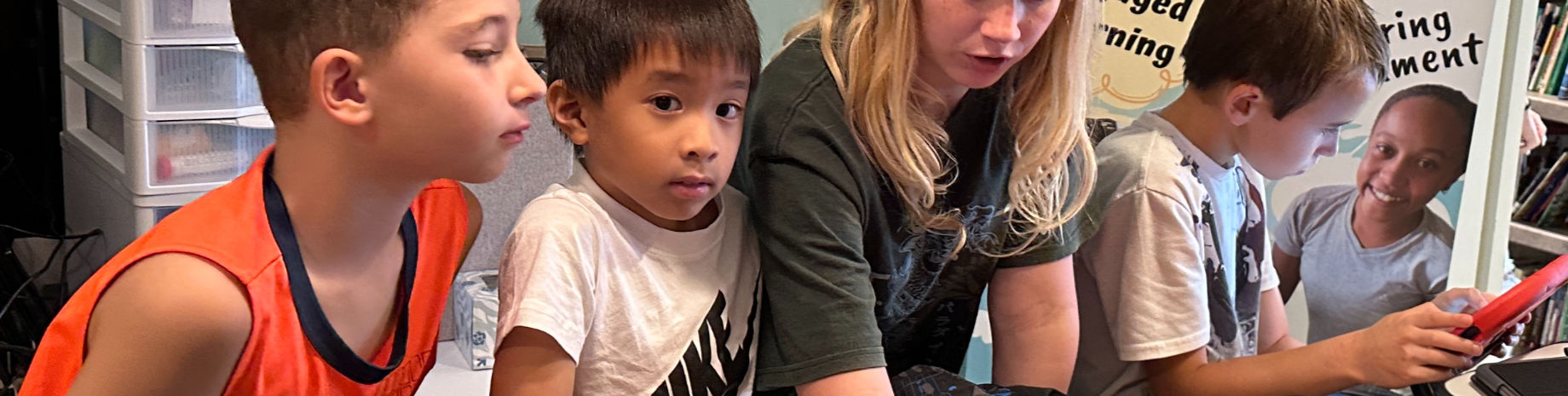 Teacher helping middle school students with tablets in a personalized learning session